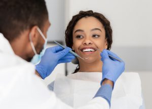A woman sits still and smiles during her oral cancer screening